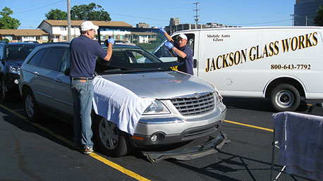 A photograph of Jackson Glass Works employees installing a windshield